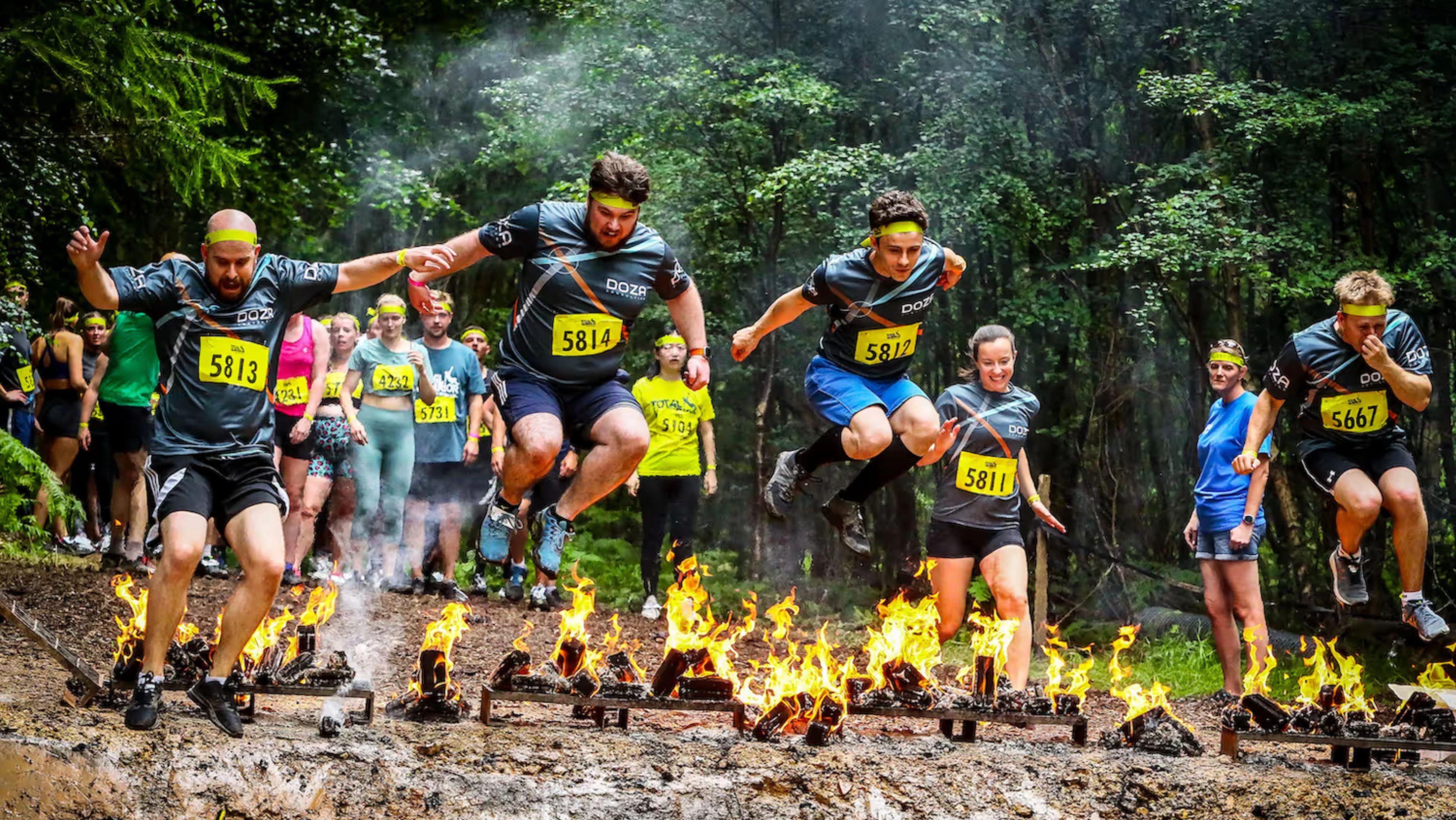 Doza team jumping over fire at Tough Mudder